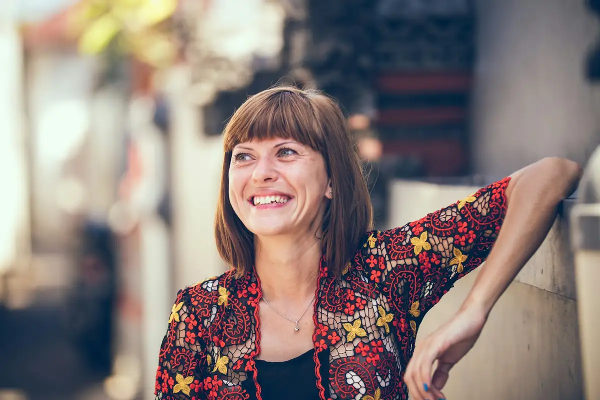 A woman in her forties smiling, looking ahead in warm daylight